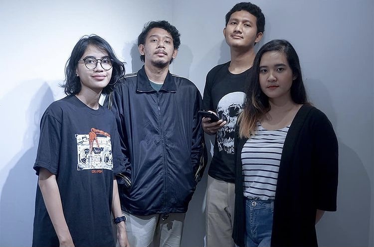 Group picture of Studio 4oo2. Group picture from Studio 4oo2. The four young Indonesian people look into the camera. The woman on the left has glasses, a black T-shirt with a radio on it, the man next to her hands in his jacket, one next to him holds a cell phone in his hand and has a black T-shirt with a skull illustration on it and the young woman on the right wears a striped blouse.