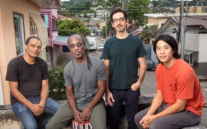 Four men look into the camera. In the background a housing estate.