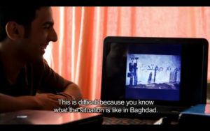 There is a person watching pictures on the computer. The picture says 'This is difficult because you know what the situation is like in Baghdad'.