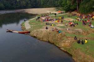 People gather on the bank of a river for a musical performance