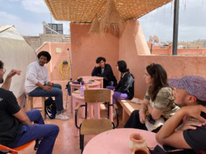 Menschen sitzen auf einer Dachterrasse und nehmen an einem Künstler*innenworkshop teil