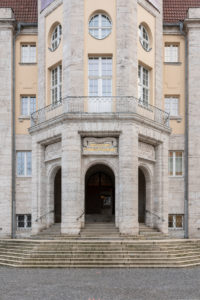 The photo shows the facade of the entrance area of Hessisches Landesmuseums. Above the middle of the three stone door arches is written in golden color: 