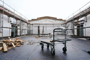 Interior view of the hall without wooden roof, in the middle there is a transport trolley.